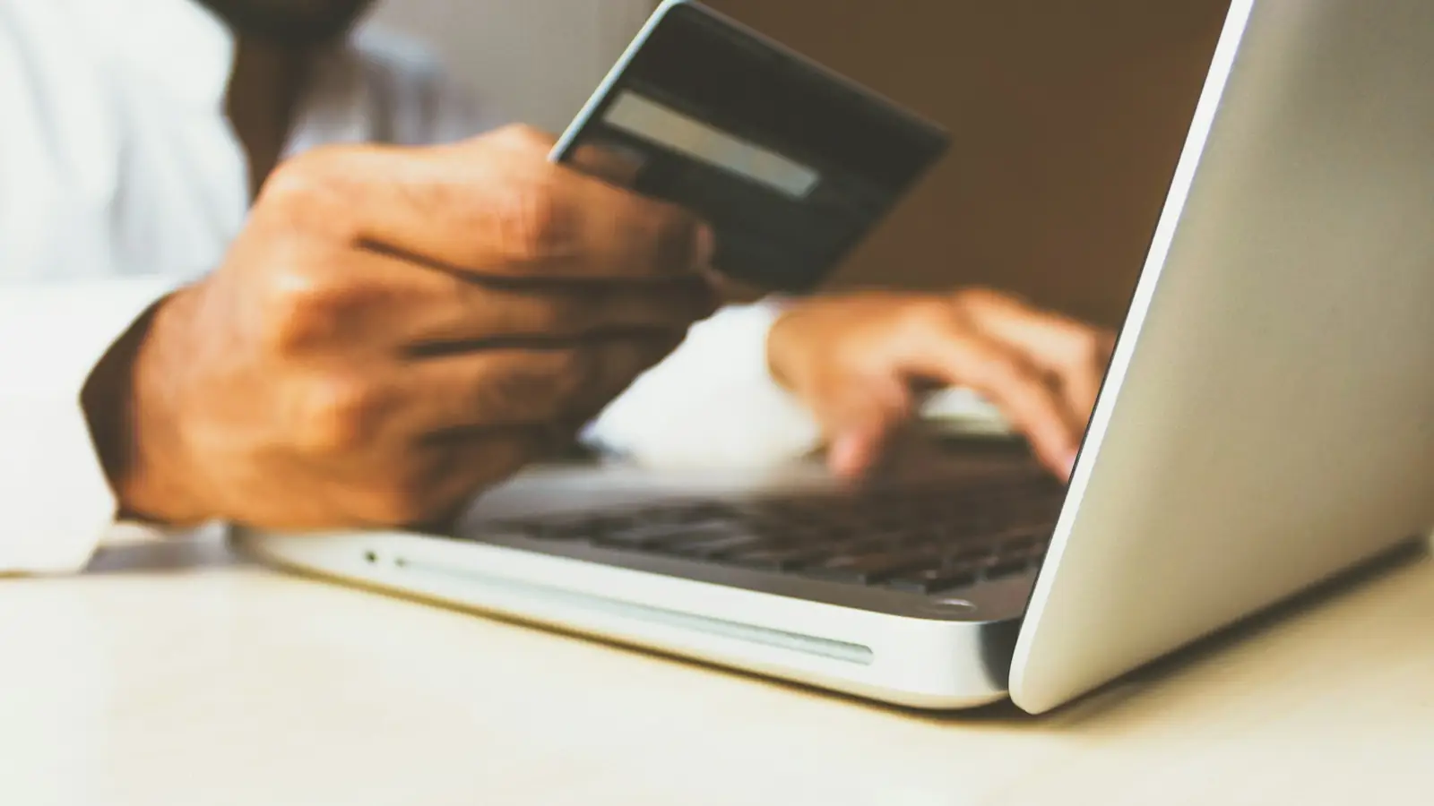 Shopper paying online with a card at a laptop